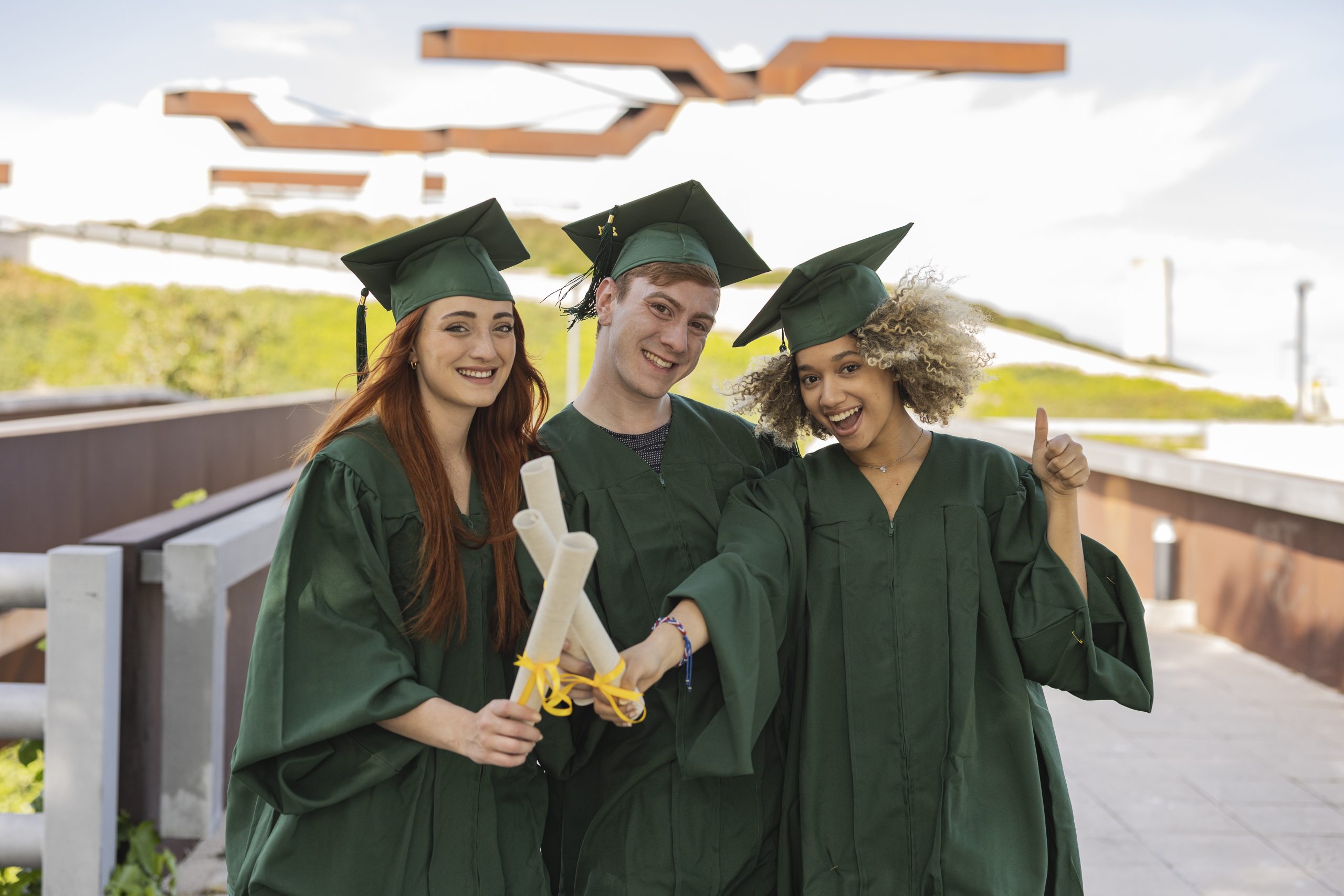 Photo of a group of multiracial young people taking selfies with one on graduation day. University campus